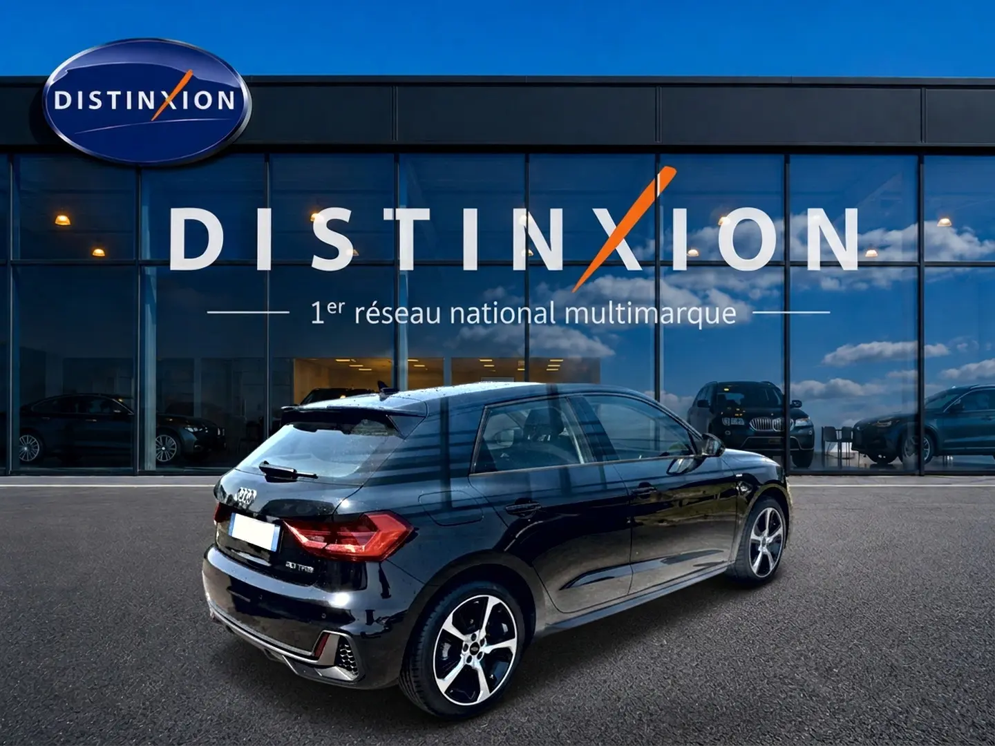 Audi A1 Sportback noir vue 3/4 arrière droit, avec jantes alu et becquet arrière devant vitrine Distinxion.
