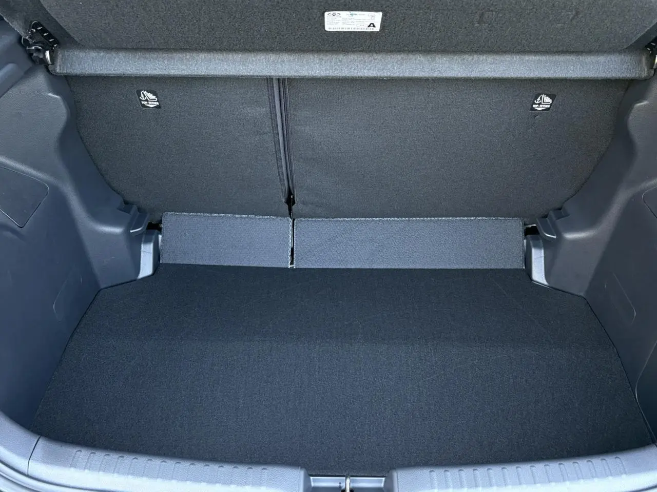 Coffre ouvert de la Toyota Yaris Hybride 2025 noir intense, montrant l'espace de chargement intérieur propre et spacieux.