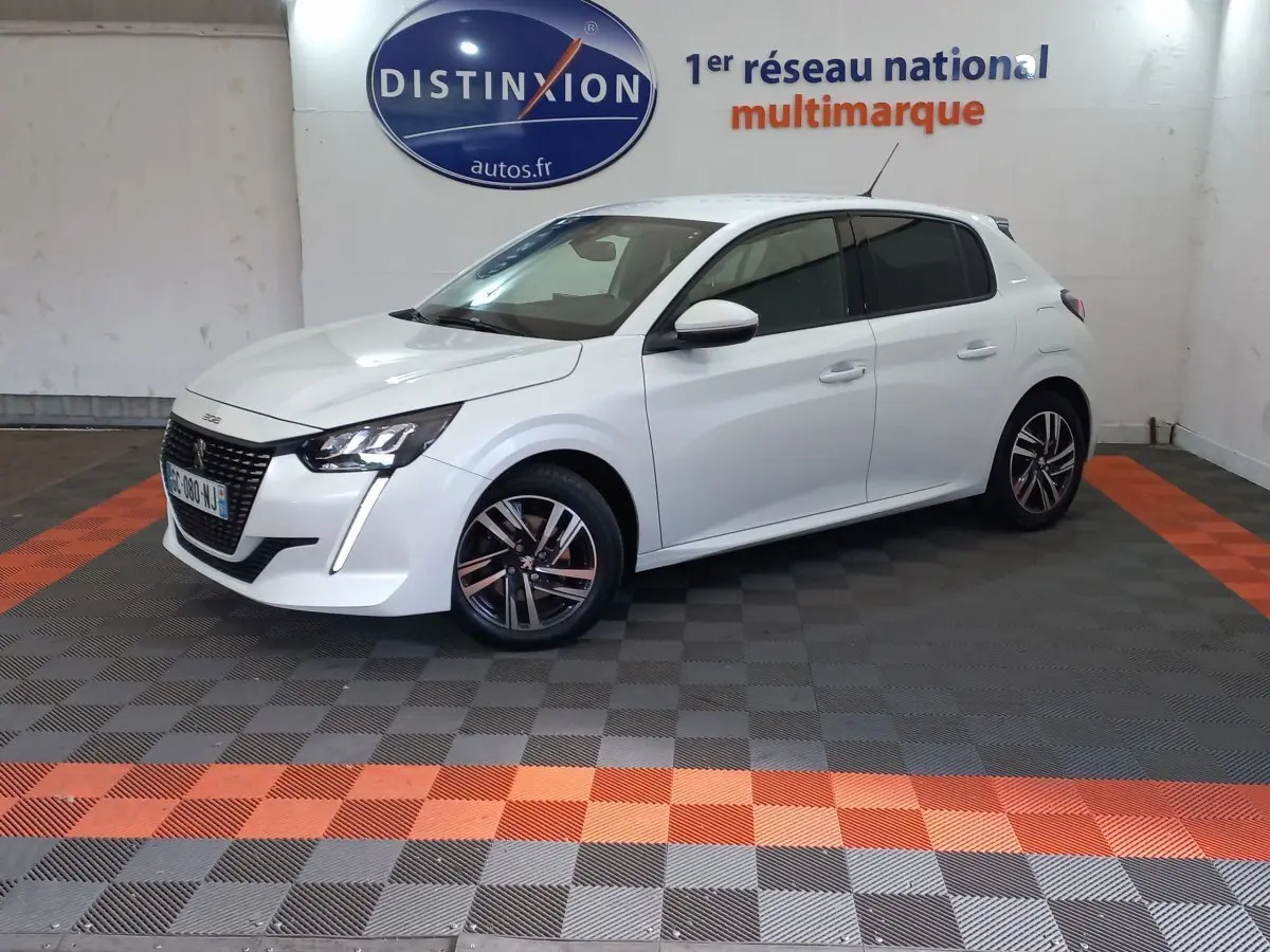 Peugeot 208 PureTech 100 blanc en 3/4 avant droit, avec phares LED et jantes alliage distinctives.