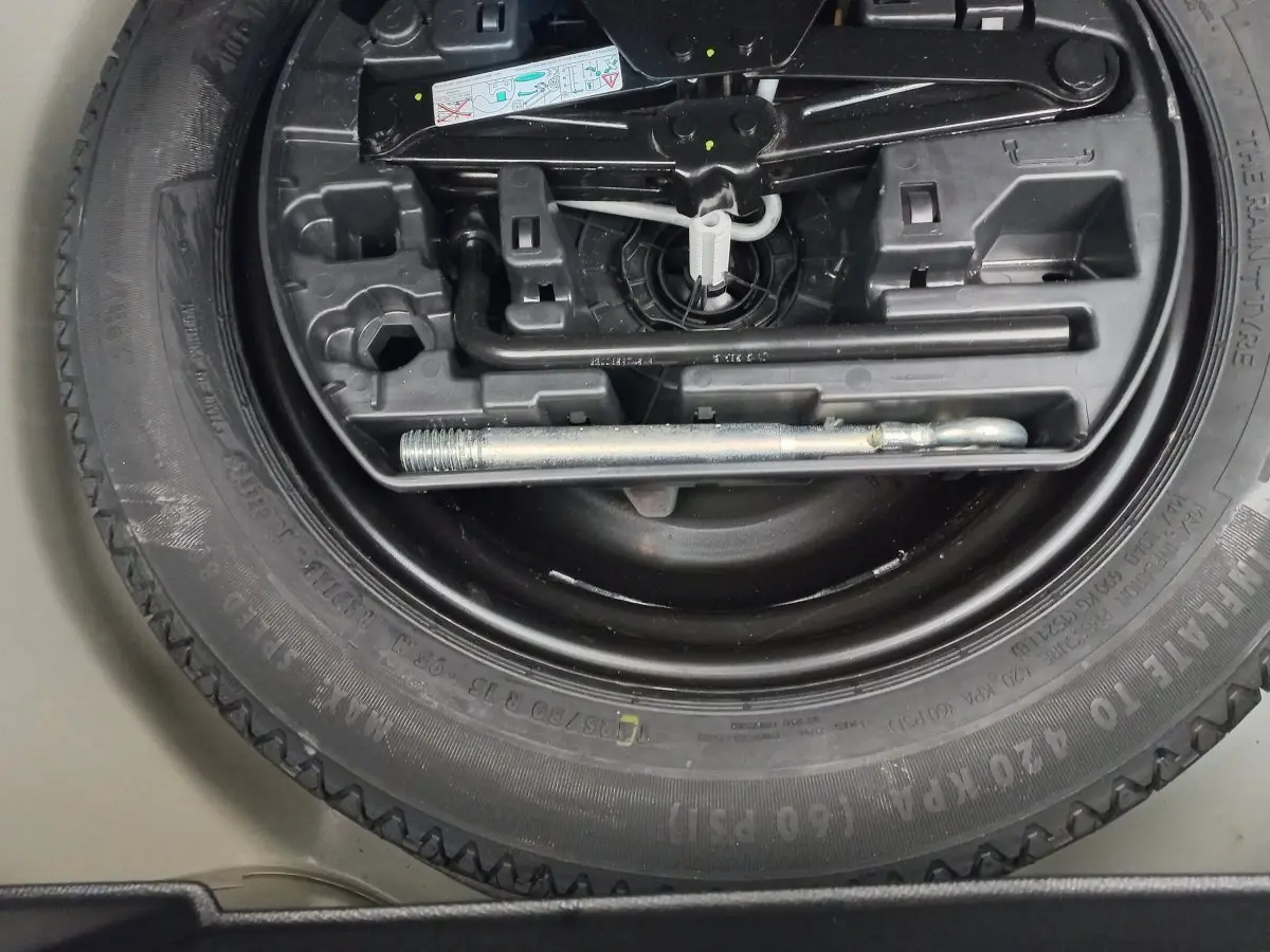 Gros plan sur la roue de secours et les outils de bord du coffre d'une Peugeot 208 blanche 2021.