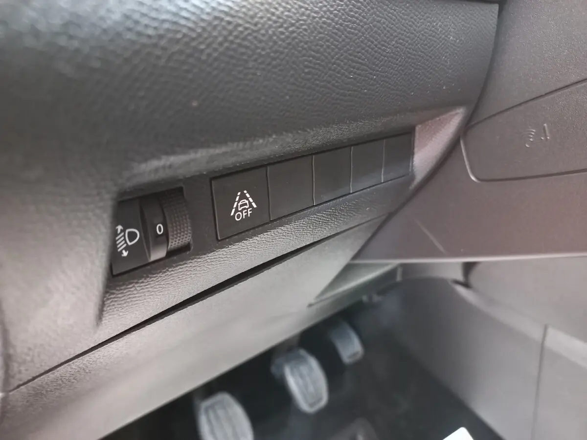 Détail des commandes côté gauche sous le tableau de bord de la Peugeot 208 blanche PureTech 100 S&S Allure 2021.