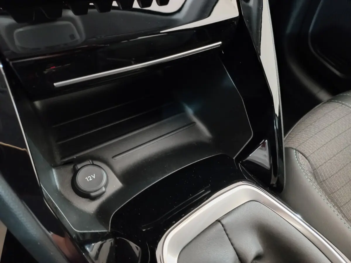 Prise 12V et rangement noir brillant près du levier de vitesse, intérieur tissu gris de la Peugeot 208 PureTech 100 Allure 2021.