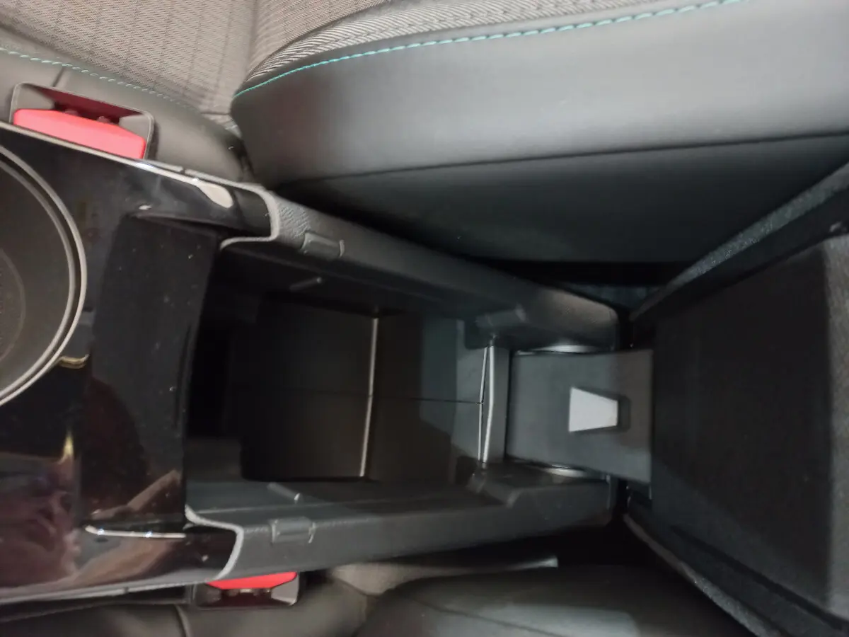 Vue rapprochée de la console centrale noire entre les sièges avant d'une Peugeot 208 blanche PureTech 100 S&S Allure 2021.