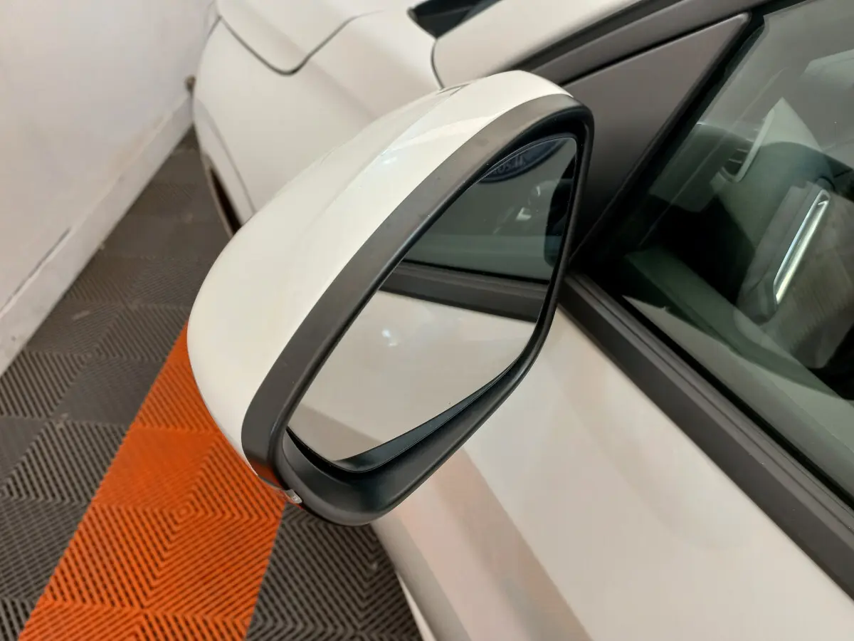 Rétroviseur côté gauche blanc de la Peugeot 208 PureTech 100 S&S Allure 2021 avec carrosserie blanche visible en arrière-plan.