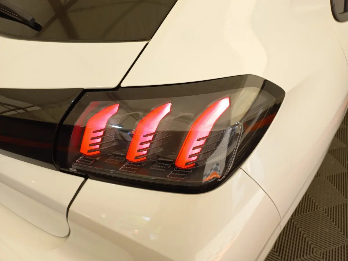 Gros plan sur le feu arrière droit rouge et noir d'une Peugeot 208 blanche PureTech 100 S&S Allure 2021.