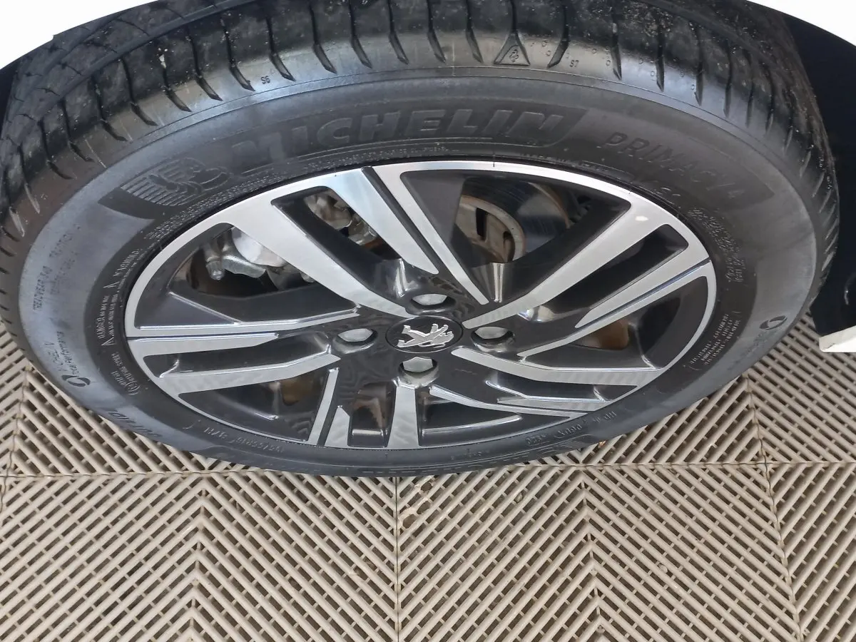 Gros plan sur la roue avant droite de la Peugeot 208 blanche avec jante alliage et pneu Michelin.