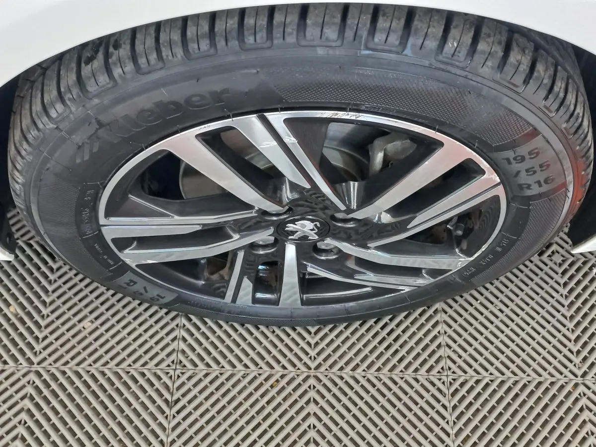 Gros plan sur la roue avant droite blanche d'une Peugeot 208 PureTech 100 S&S Allure avec jante alliage noire et argent.