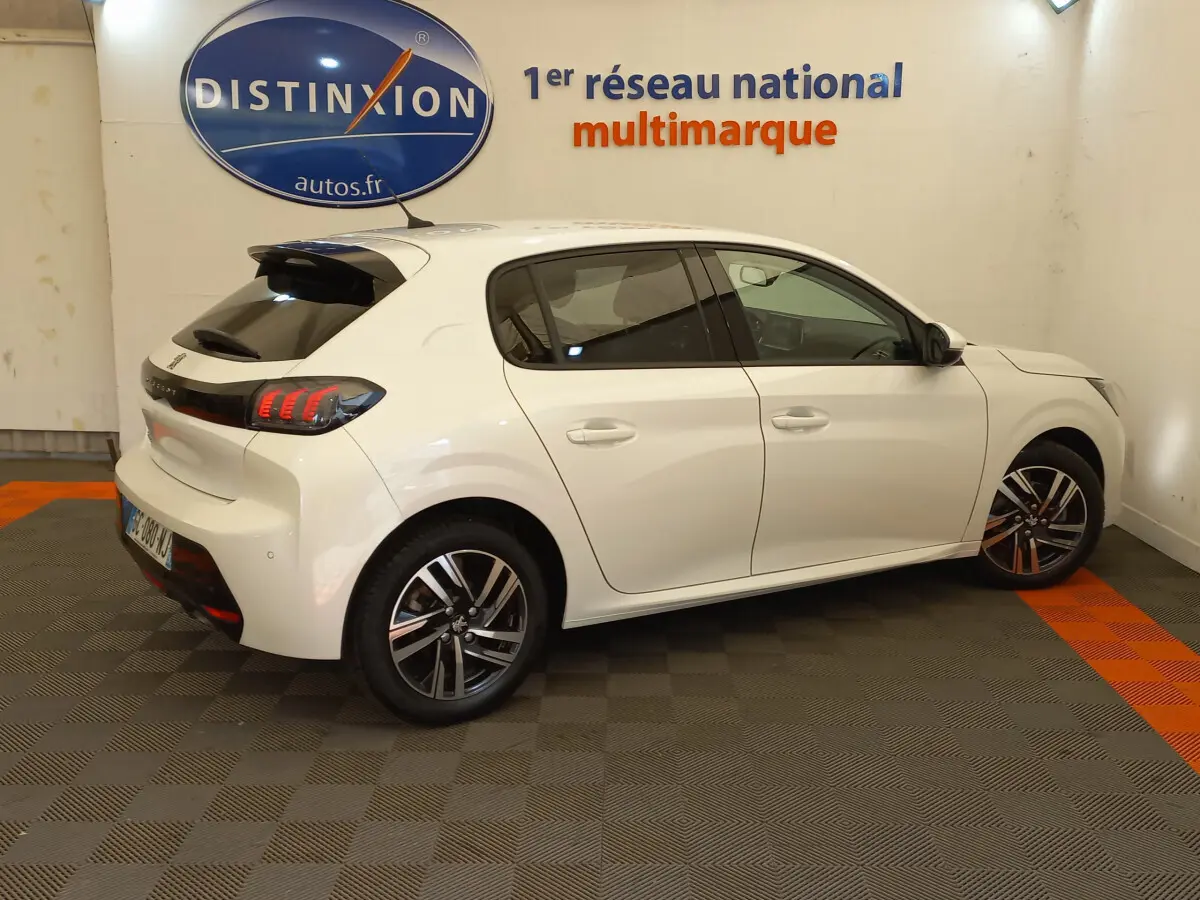 Vue côté gauche d'une Peugeot 208 blanche PureTech 100 S&S Allure avec feux arrière LED et jantes alliage.