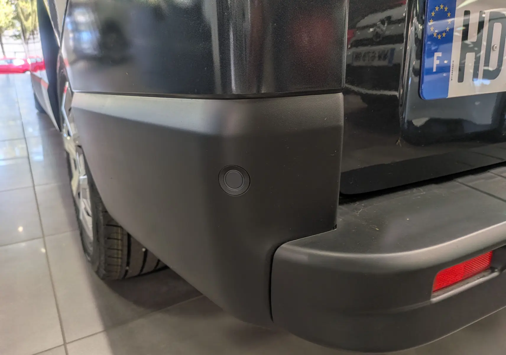 Gros plan sur le pare-chocs arrière gris comète du Renault Trafic Combi avec capteur de recul visible.