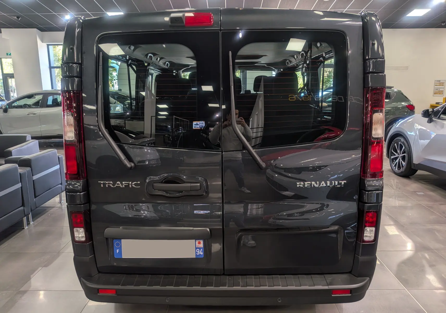 Vue arrière du Renault Trafic Combi gris Comète 2025, avec portes vitrées et essuie-glaces verticaux visibles.