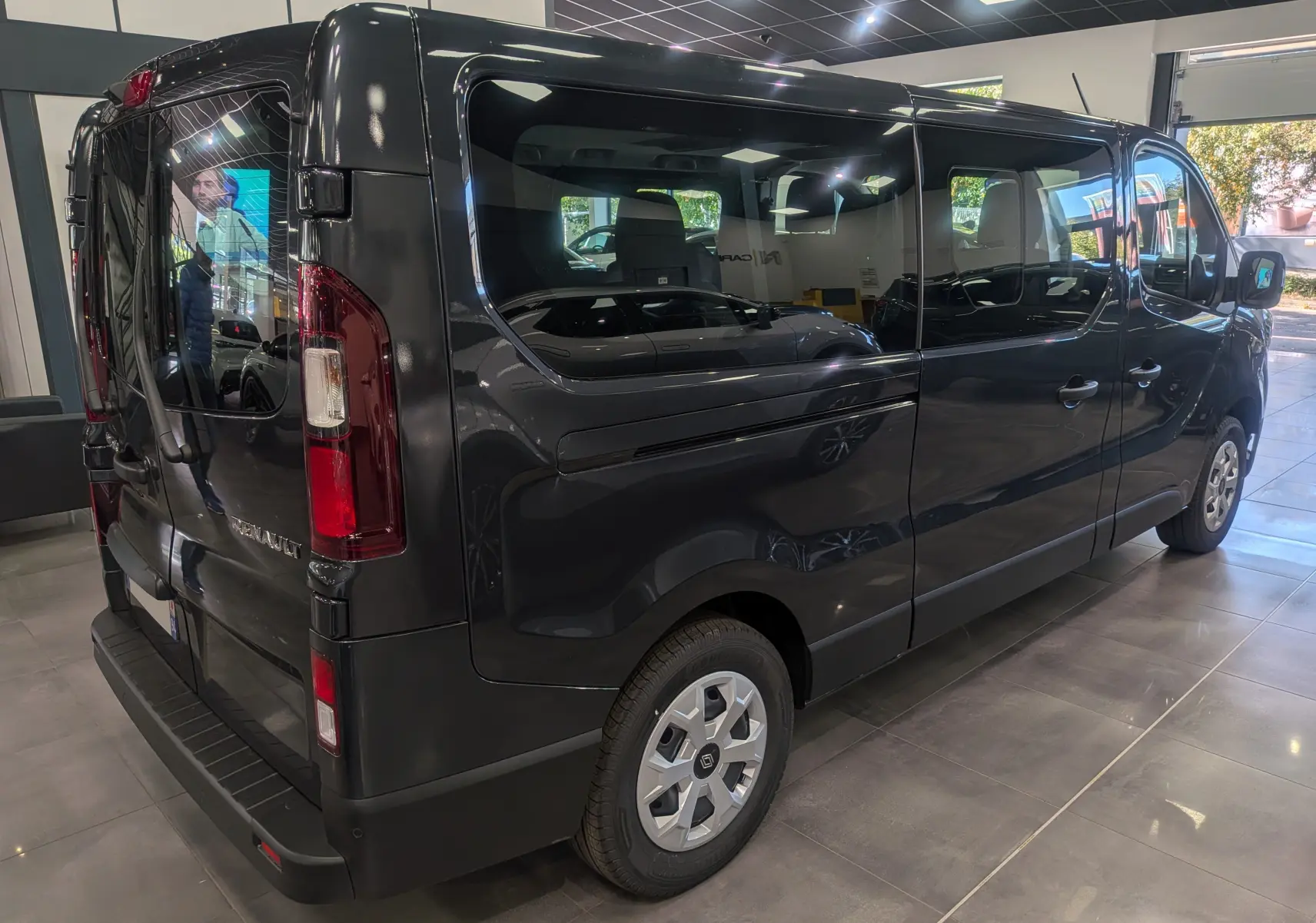Renault Trafic Combi gris Comète vu en 3/4 arrière droit, mettant en valeur ses grandes vitres latérales teintées.