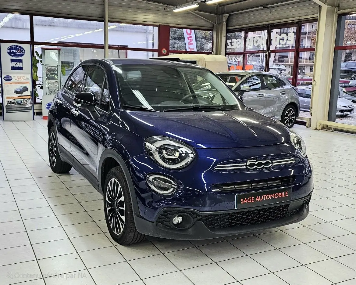 Vue 3/4 avant d'une FIAT 500X bleu nuit 2024 en hybride essence, avec calandre et phares ronds distinctifs en showroom.