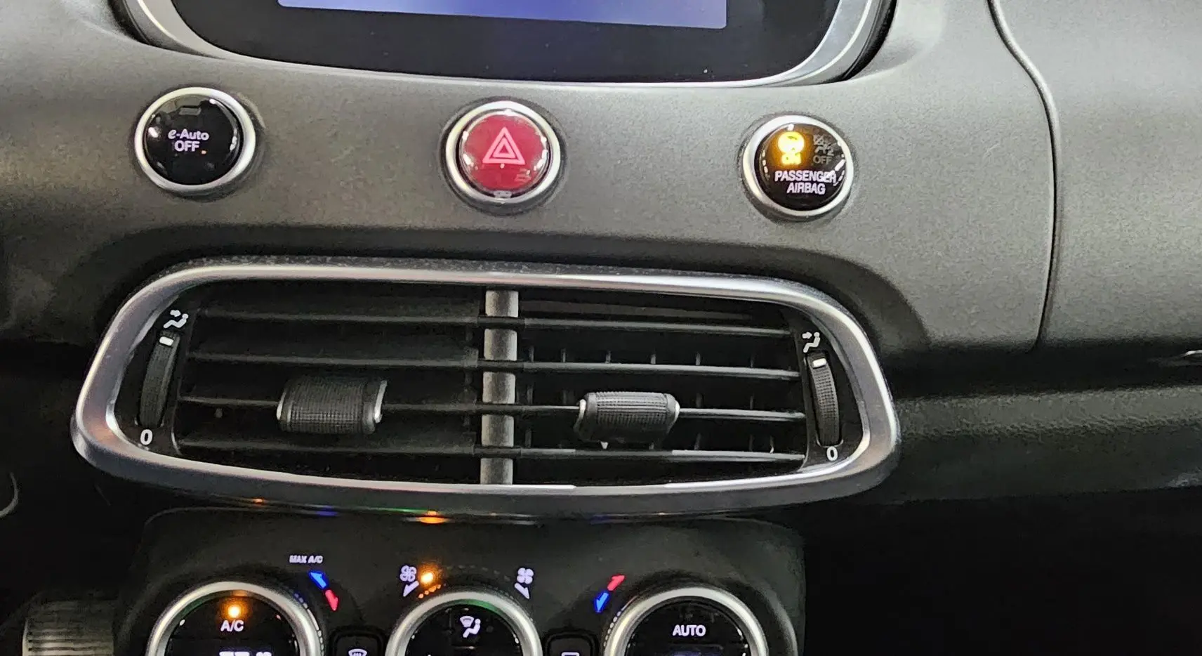 Détail du tableau de bord de la FIAT 500X 2024 montrant les commandes de climatisation et les aérateurs centraux noirs.