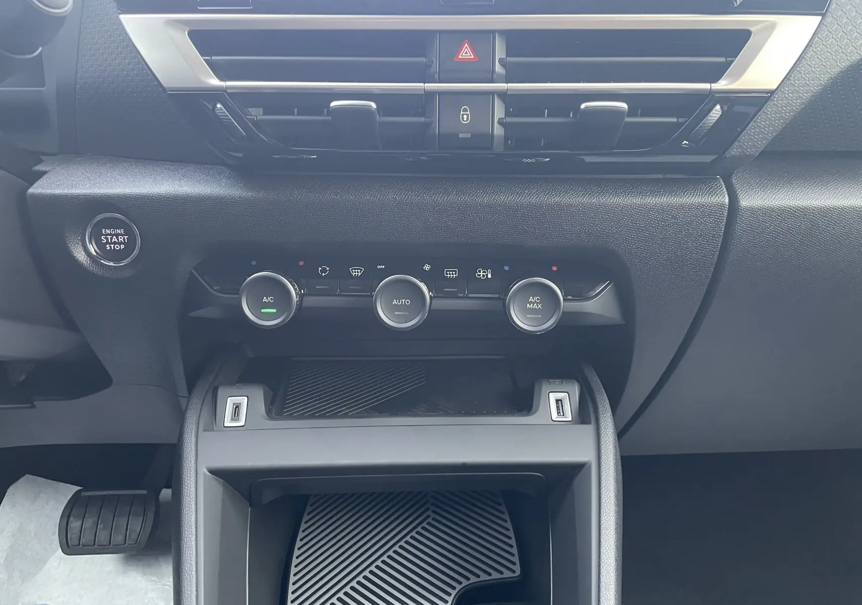 Vue rapprochée du tableau de bord noir de la Citroën C4 hybride 2025, avec commandes climatisation et bouton start/stop.