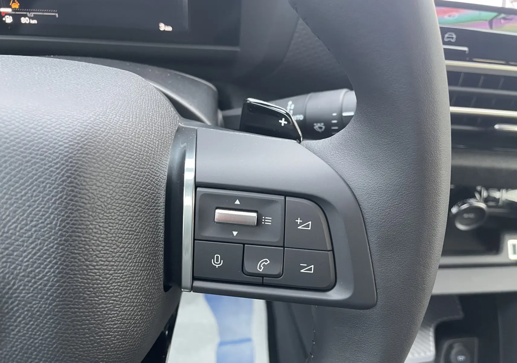 Gros plan sur les commandes au volant à gauche du Citroën C4 hybride 2025, intérieur noir avec boutons multifonctions.