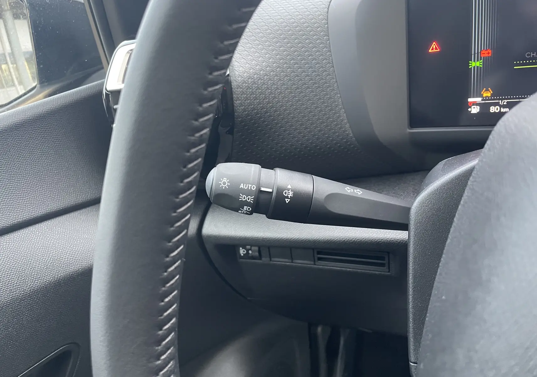 Gros plan sur la manette de clignotants à gauche du volant dans l’habitacle noir du Citroën C4 hybride 2025.