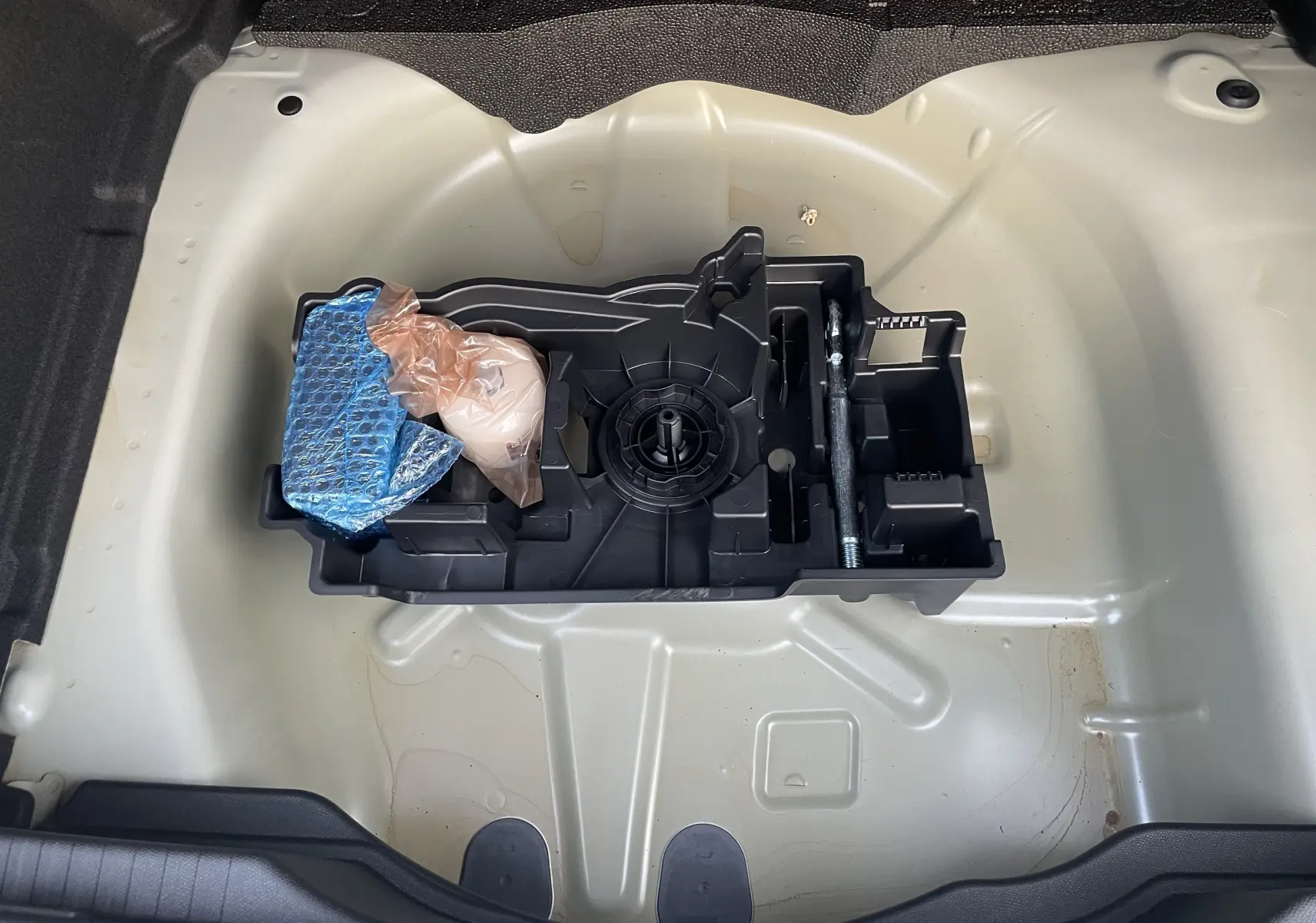 Vue plongeante sur le coffre ouvert de la Citroën C4 hybride blanche, montrant le rangement pour roue de secours et outils.