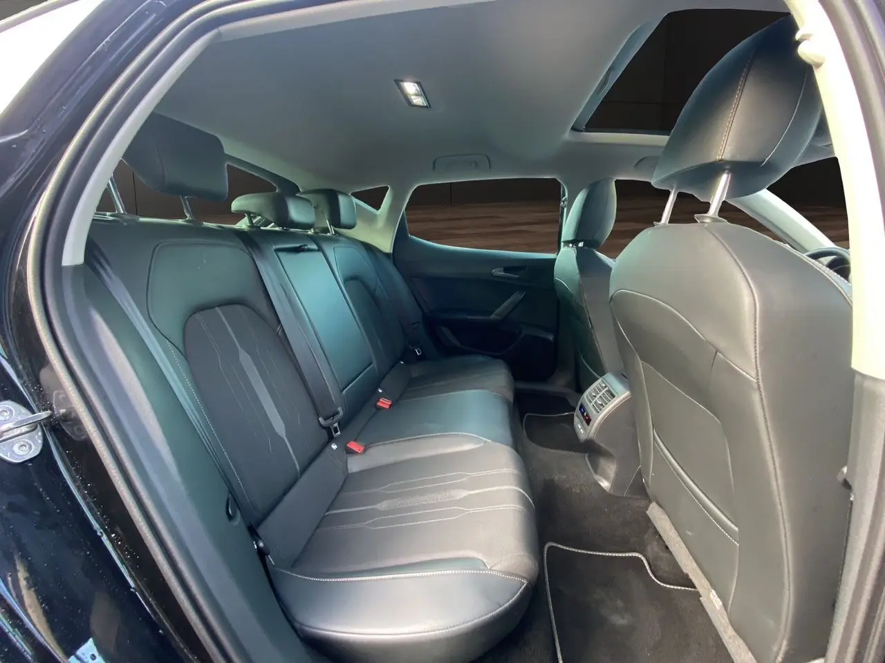 Vue intérieure arrière de la CUPRA Leon 2023 noire, montrant les sièges en cuir noir et le toit ouvrant panoramique.