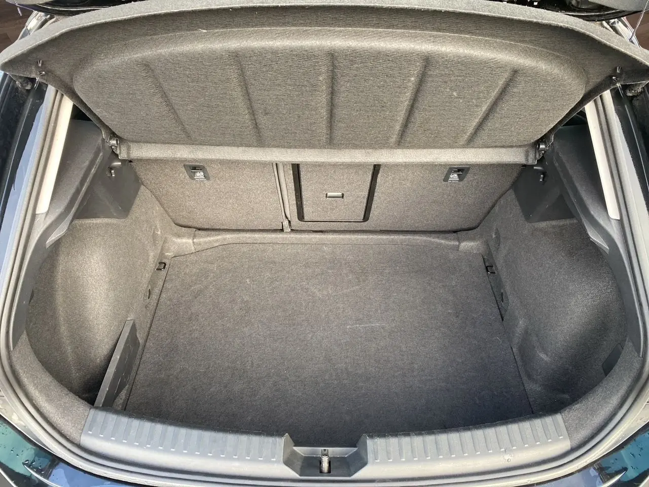 Coffre ouvert vu de dessus d'une CUPRA Leon noire 2023, montrant l'espace de rangement intérieur vide et la trappe arrière.