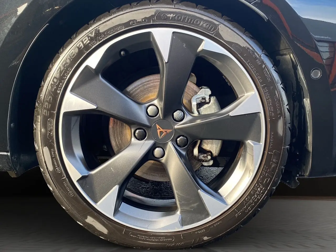 Gros plan sur la jante alliage bi-ton gris et noir d’une CUPRA Leon noire avec logo Cupra au centre.