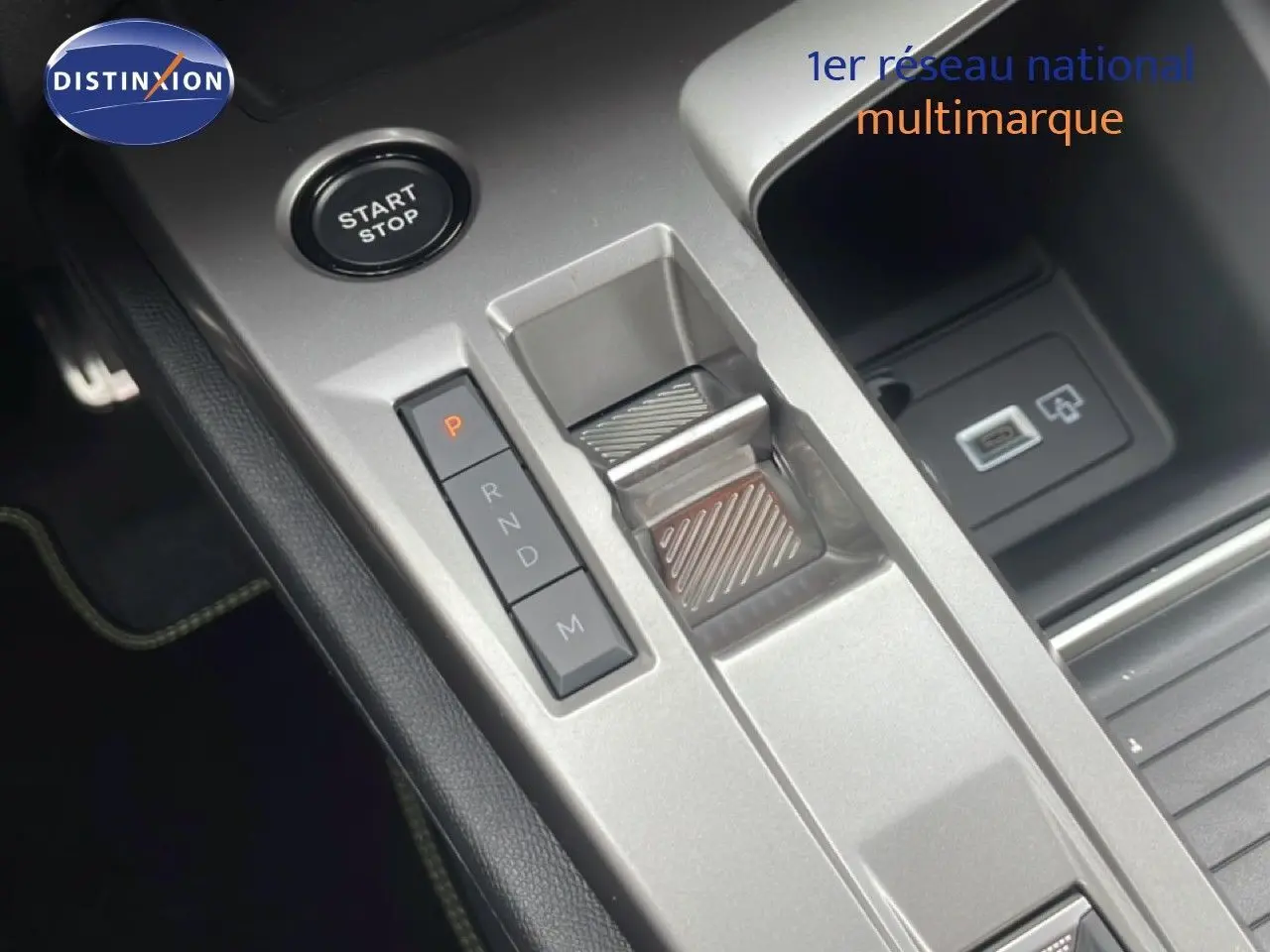 Gros plan sur la console centrale grise du Peugeot 308 Hybrid 2026, avec bouton start/stop et sélecteur de boîte automatique.