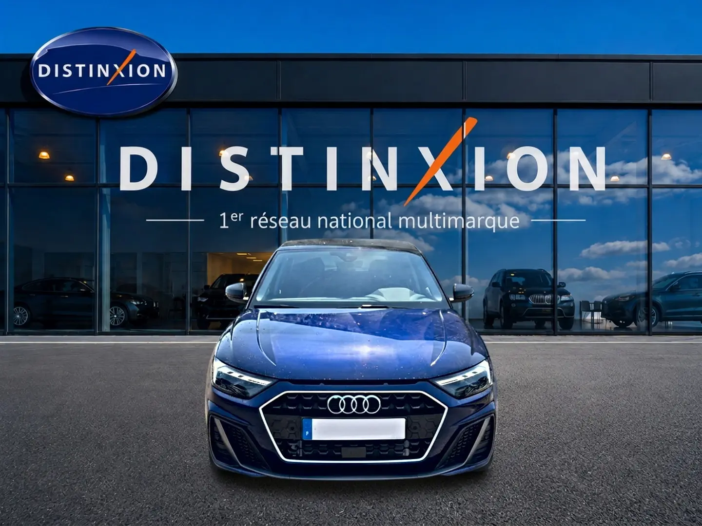 Audi A1 Sportback bleu foncé vue de face devant une vitrine avec logo Distinxion en arrière-plan.