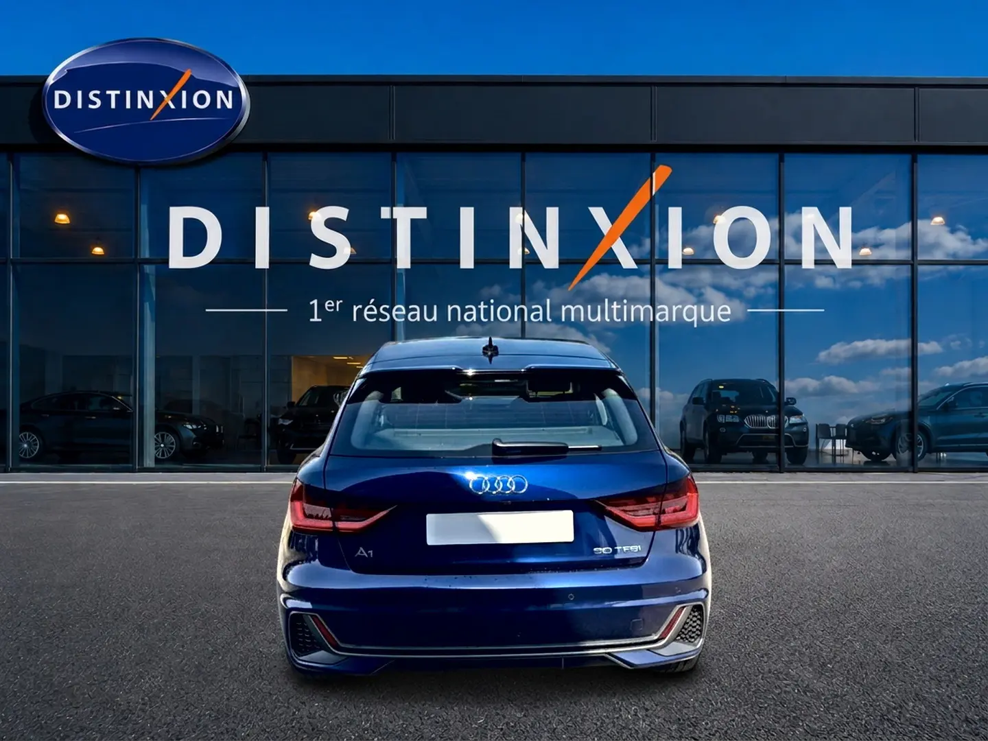 Vue arrière d'une Audi A1 Sportback 30 TFSI bleu foncé avec feux LED, garée devant une vitrine Distinxion.