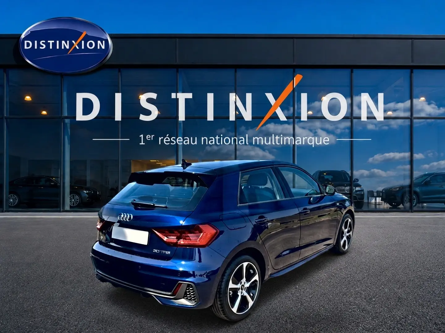 Audi A1 Sportback bleu 3/4 arrière droit, avec jantes alu et becquet arrière visible devant showroom Distinxion.