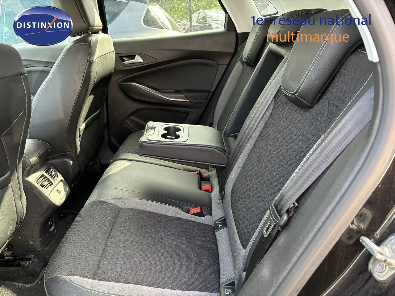 Vue intérieure côté droit des sièges arrière noirs avec accoudoir central et porte ouverte d'un Opel Grandland X 2019.