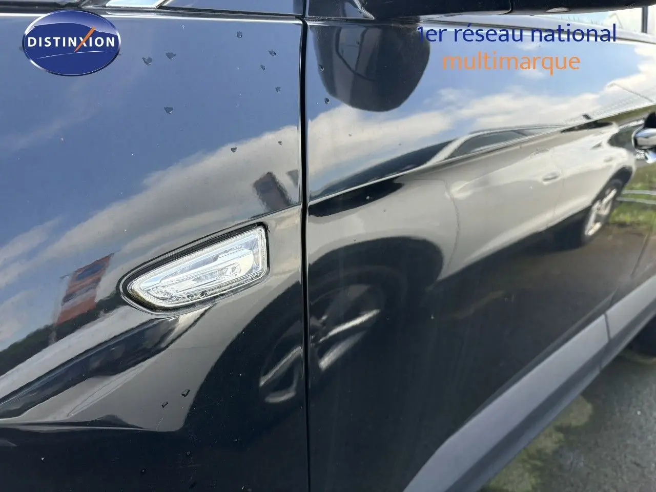 Gros plan sur le clignotant latéral droit d'un Opel Grandland X noir, reflétant un autre véhicule blanc à l'extérieur.