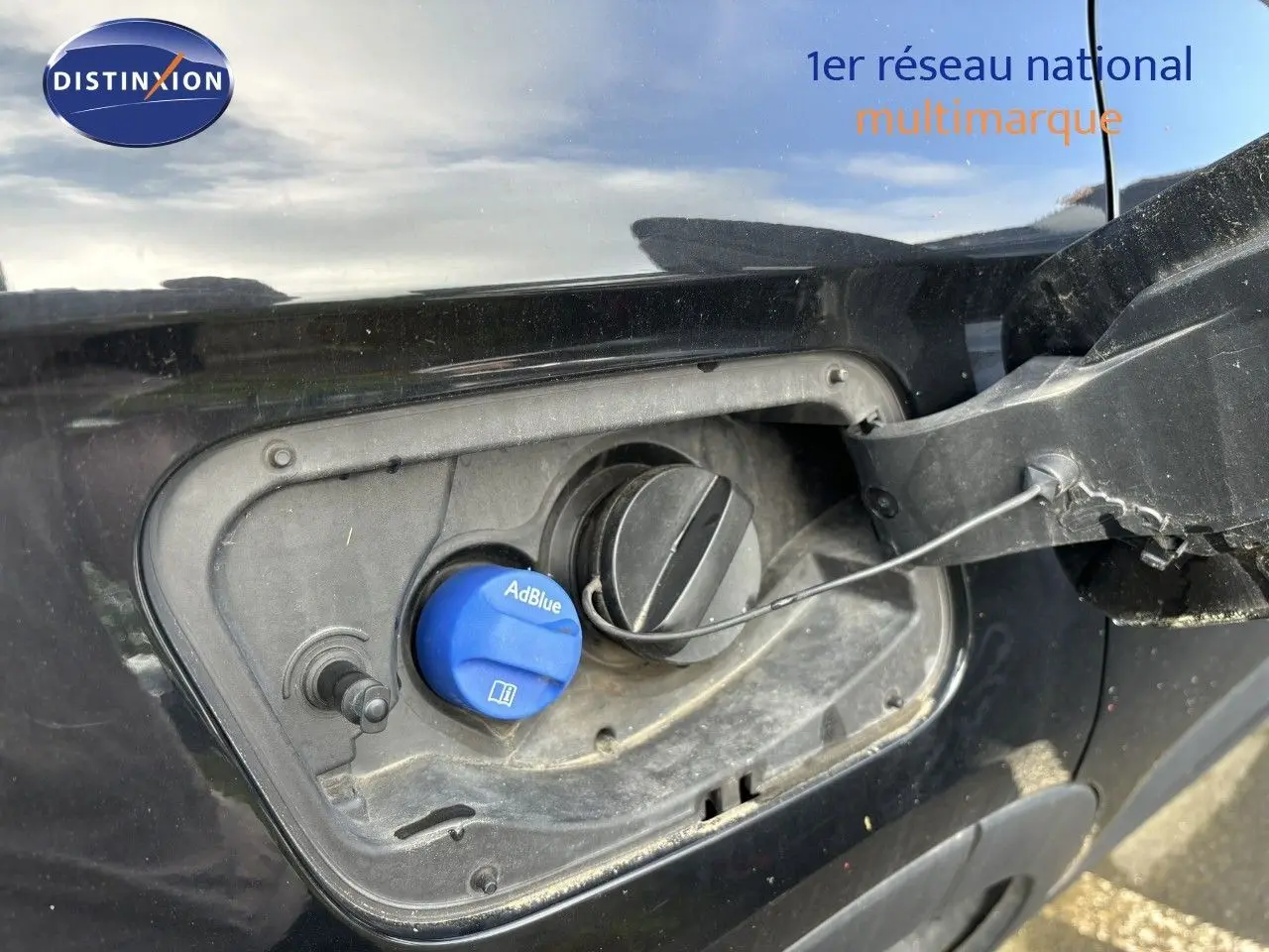 Gros plan sur la trappe à carburant noire d'un Opel Grandland X 2019 avec bouchon AdBlue bleu visible.