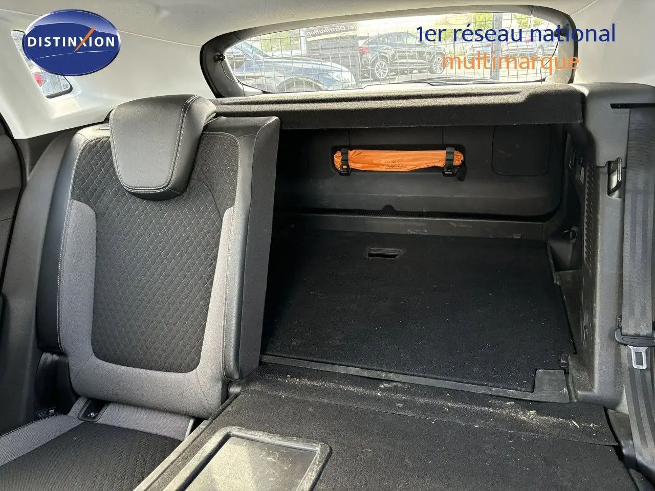 Intérieur du coffre de l'Opel Grandland X noir 2019, siège arrière rabattable et rangement avec trousse de secours orange visible.