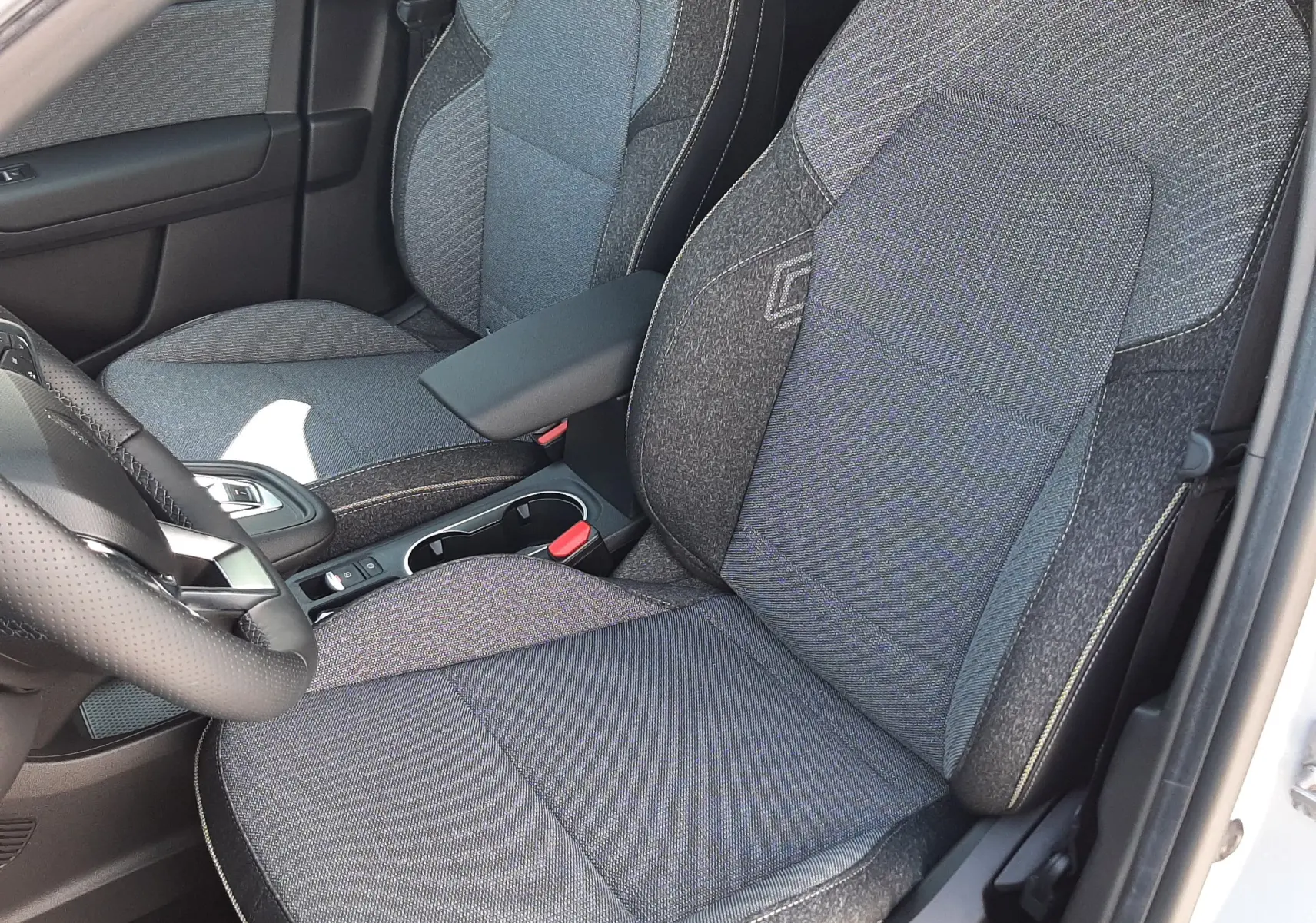 Gros plan sur les sièges avant en tissu gris du Renault Symbioz 2024, version hybride essence, intérieur soigné et moderne.