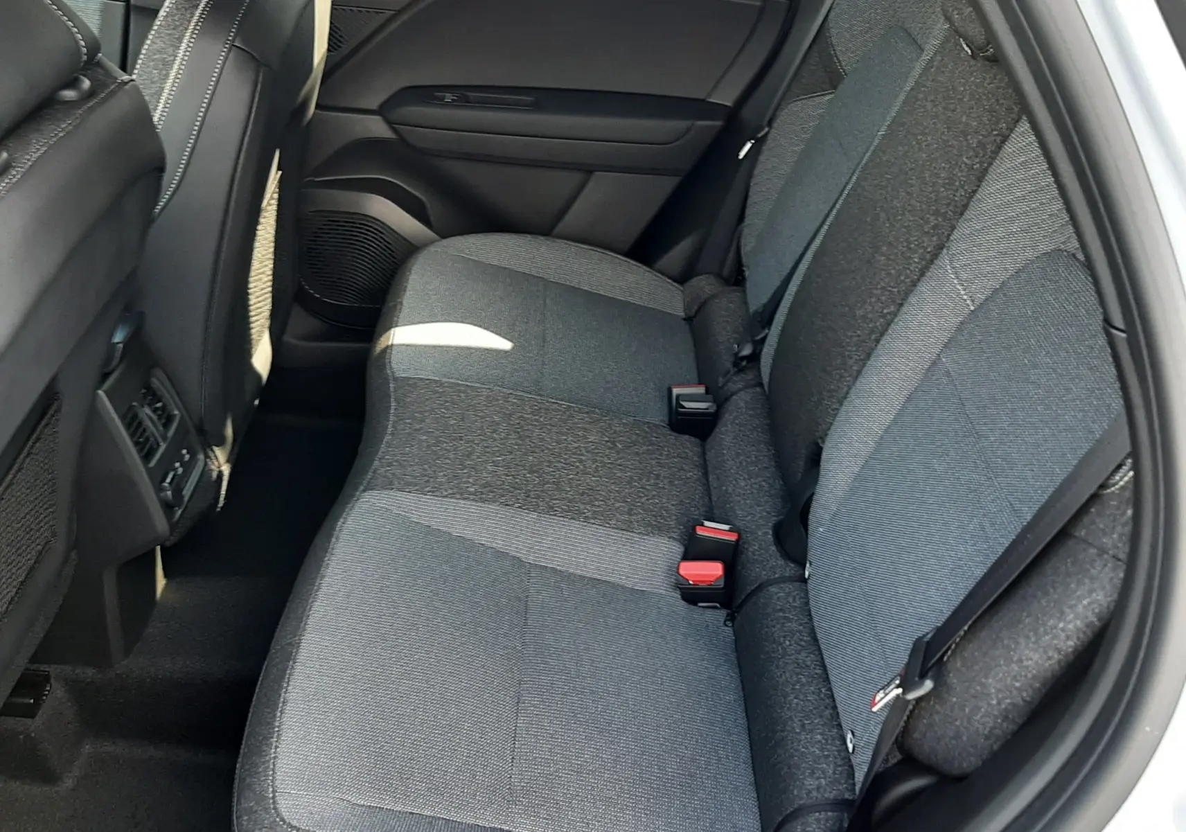 Vue latérale droite de l'arrière intérieur du Renault Symbioz 2024 avec sièges tissu gris bicolore et ceintures noires.