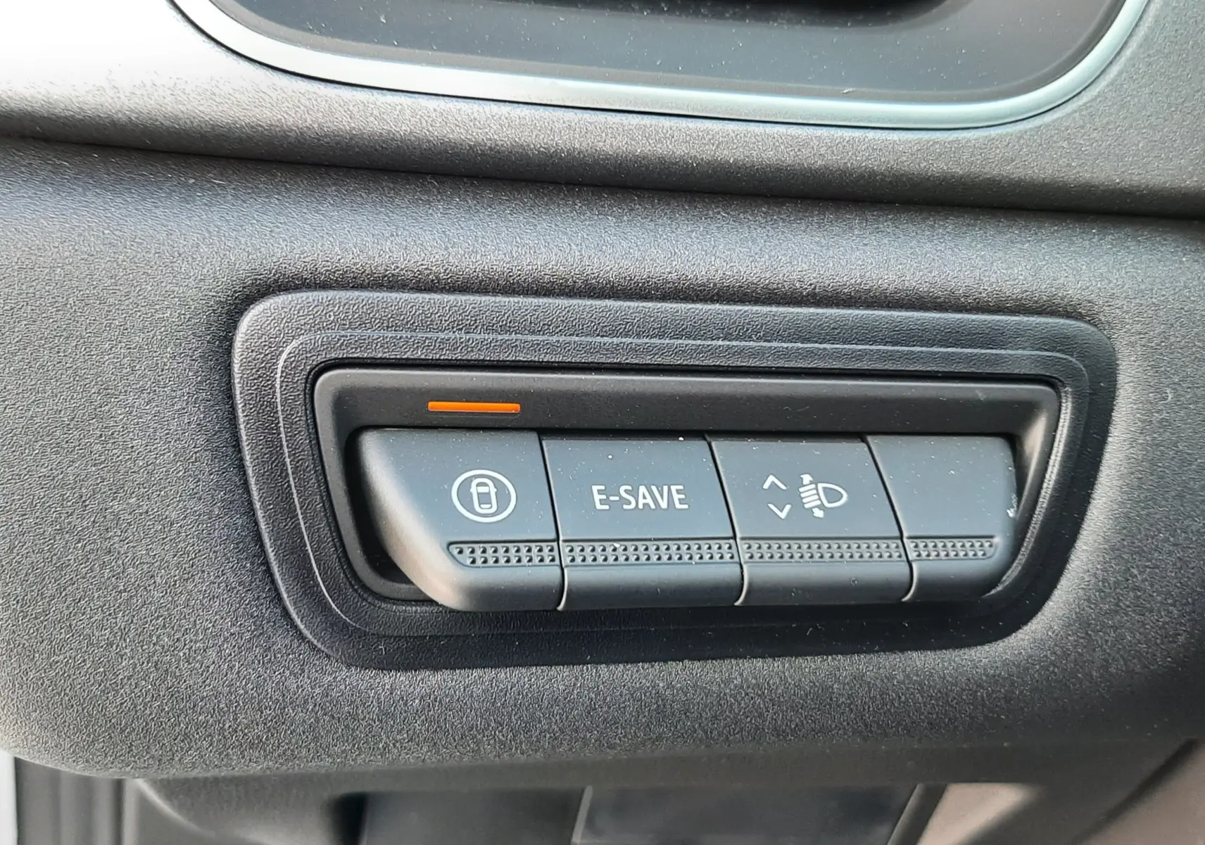 Gros plan sur les boutons de commande noirs du tableau de bord du Renault Symbioz gris Rafale, avec témoin orange allumé.