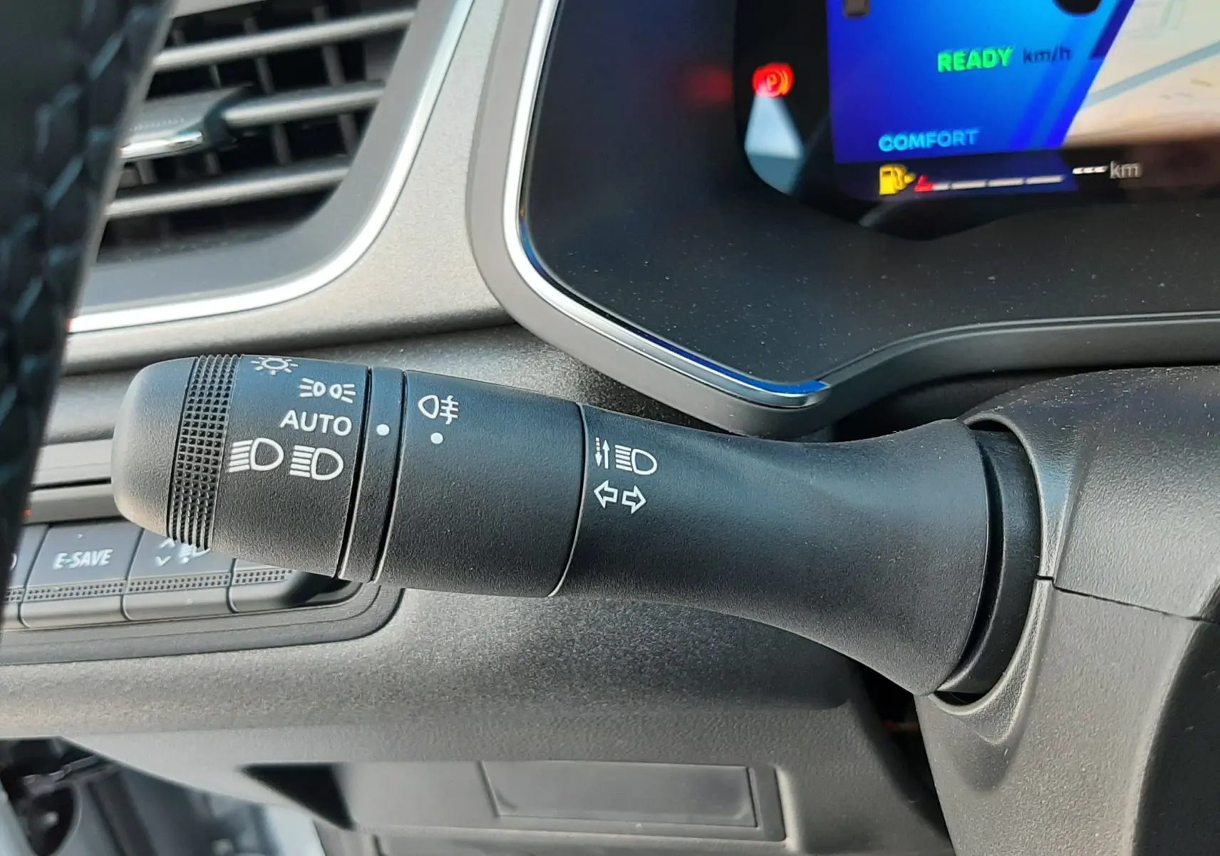 Gros plan sur la commande des phares et clignotants à gauche du volant du Renault Symbioz gris Rafale, tableau de bord numérique visible.