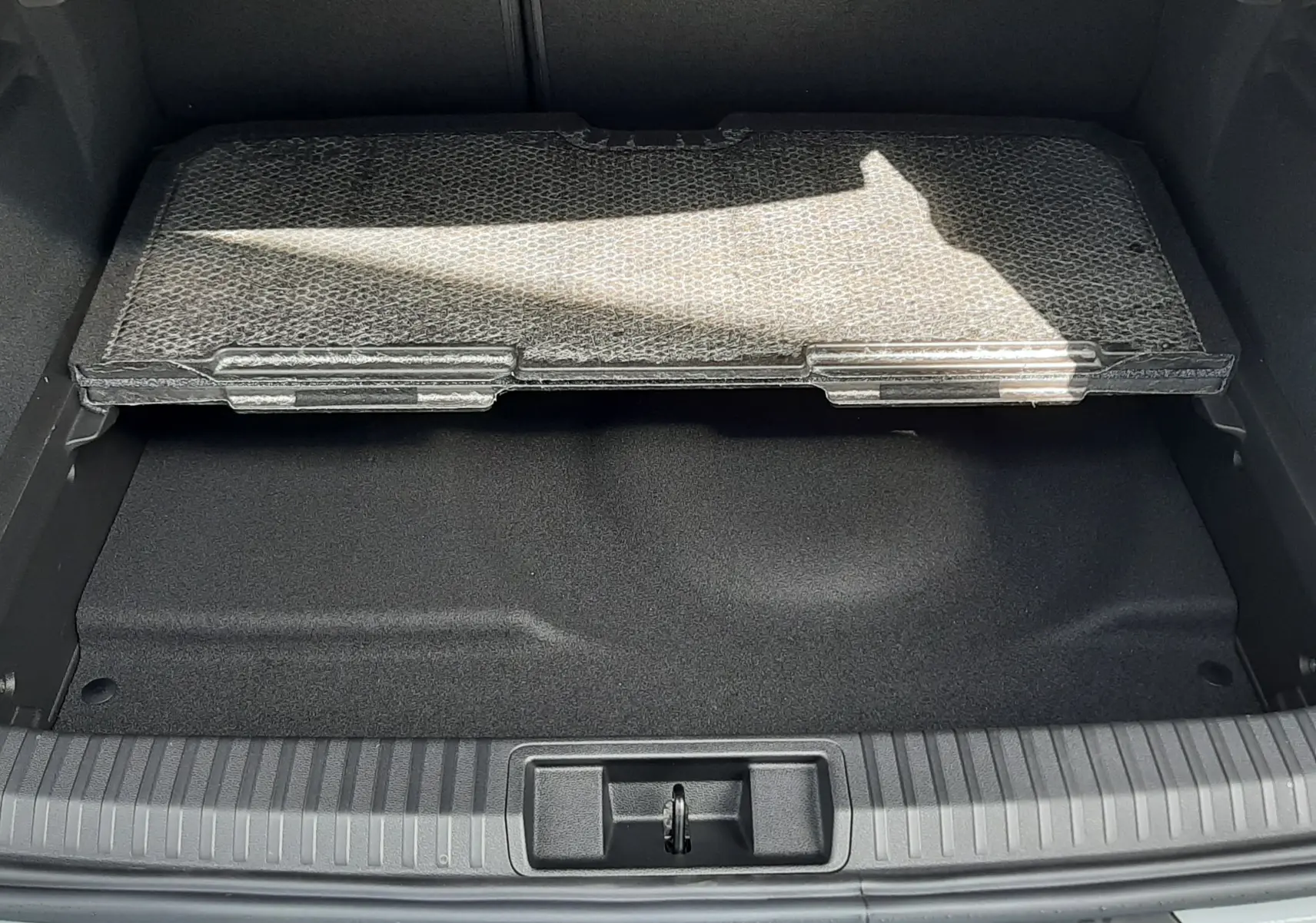 Coffre ouvert vu de l'arrière d'une Renault Symbioz gris Rafale, avec tapis de protection partiel visible.