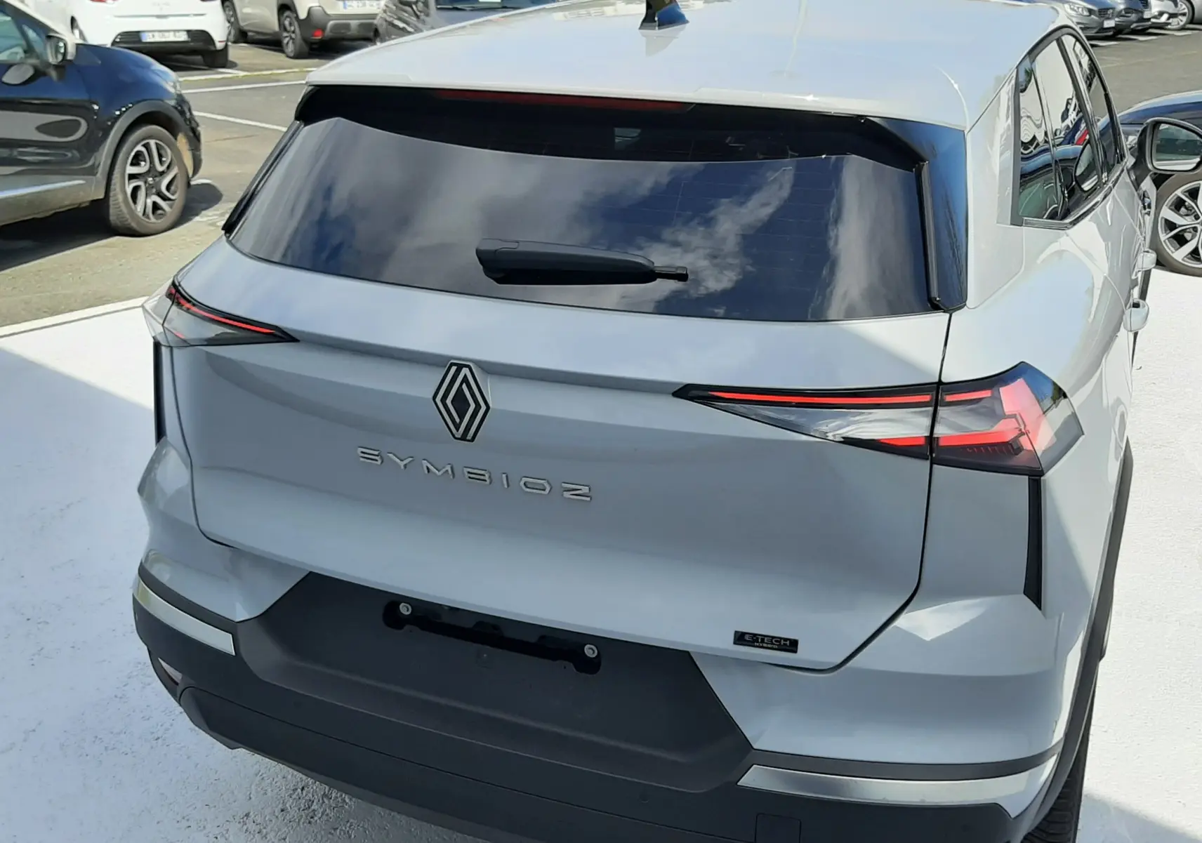 Vue arrière en léger 3/4 droit du Renault SYMBIOZ gris Rafale, soulignant ses feux arrière fins et sa lunette teintée.