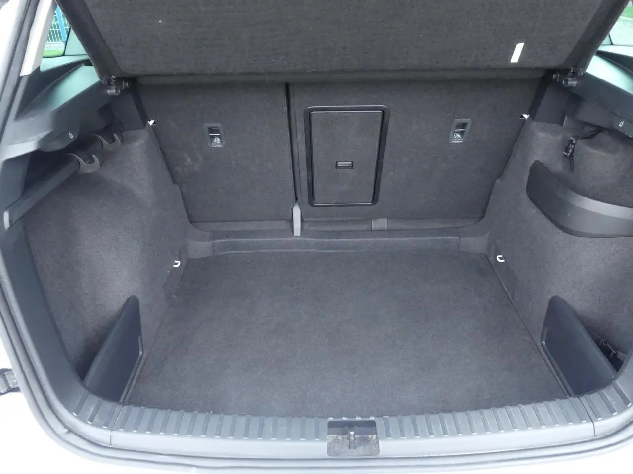 Coffre ouvert du Skoda Karoq 2024, vue intérieure montrant un espace de rangement gris foncé avec trappe centrale.