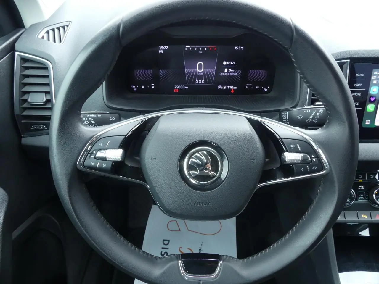 Vue frontale du volant cuir noir multifonctions et du tableau de bord digital du Skoda Karoq blanc 2024.