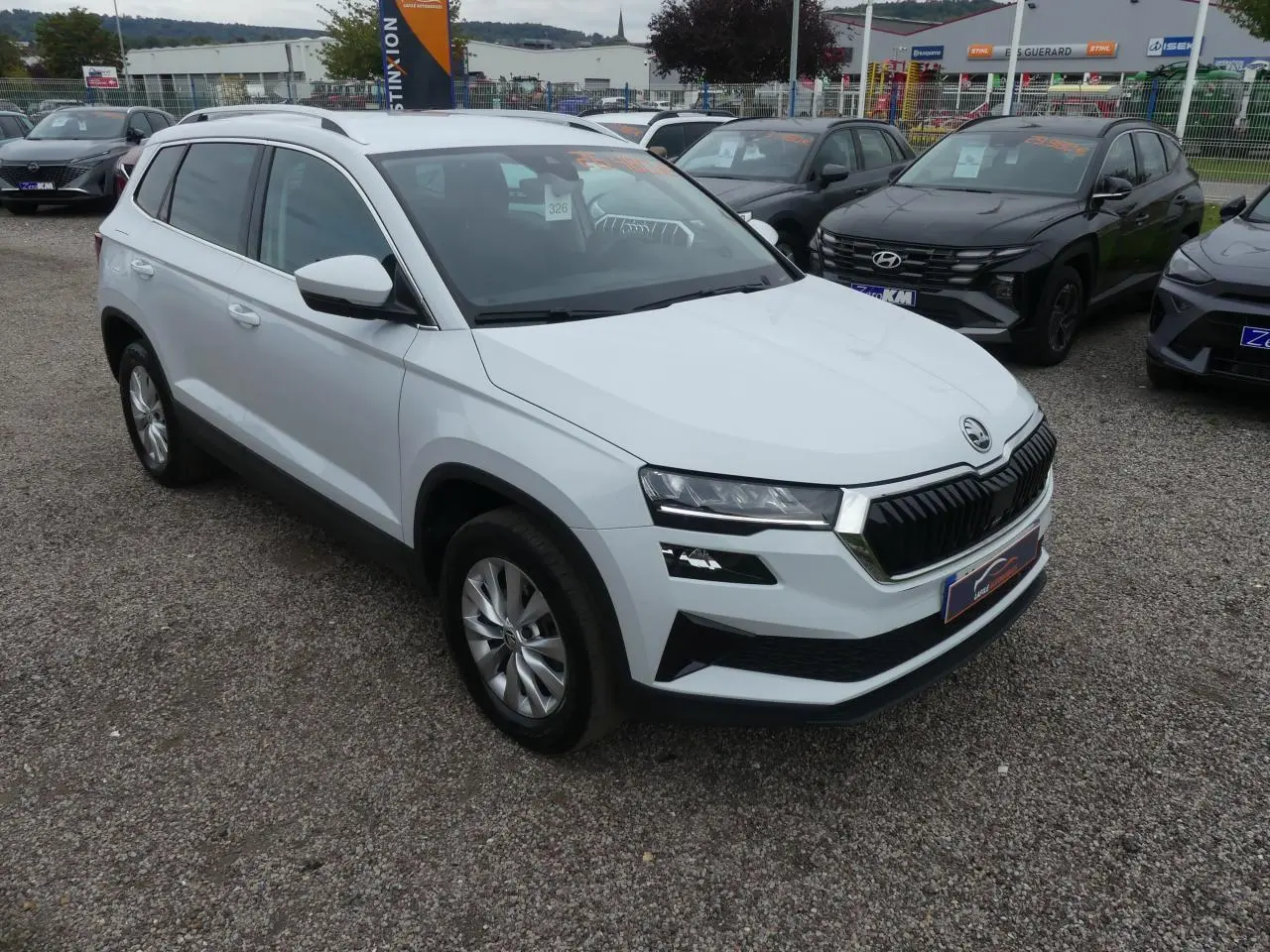 SUV SKODA KAROQ blanc en vue 3/4 avant droit, avec calandre noire et jantes alliage 17 pouces visibles.
