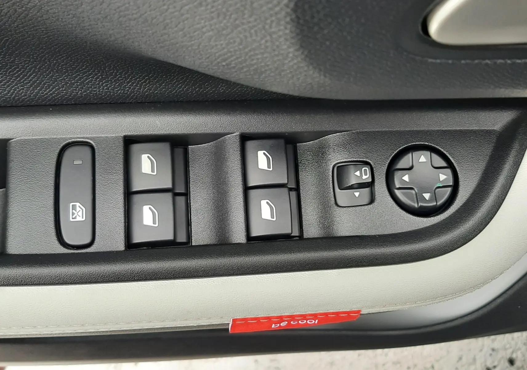 Gros plan sur les commandes de lève-vitres et réglage des rétroviseurs côté conducteur du Citroën C3 Aircross 2025 gris toit noir.