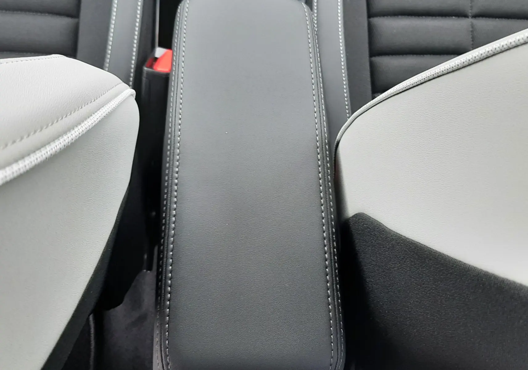 Vue plongeante sur l'accoudoir central noir entre les sièges avant gris du Citroën C3 Aircross hybride 2025.