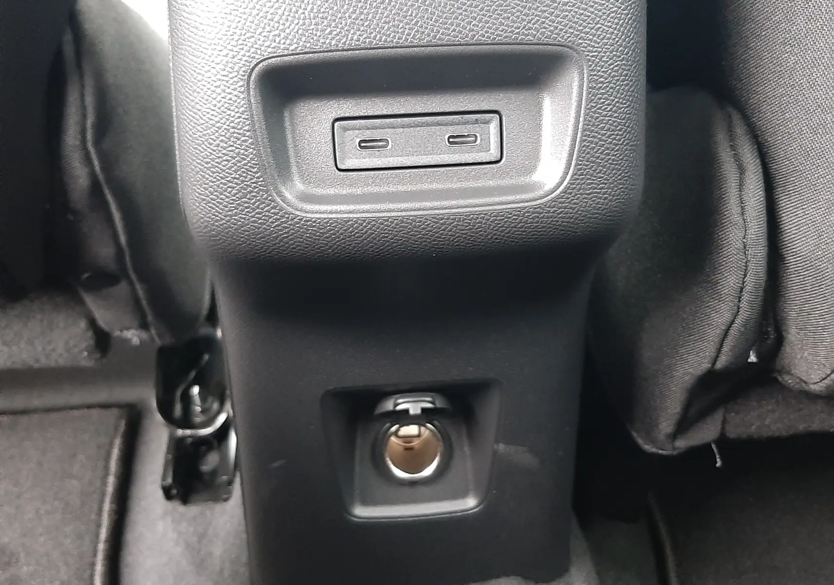 Prise USB et prise 12V en gros plan sur la console centrale arrière du Citroën C3 Aircross hybride gris toit noir.