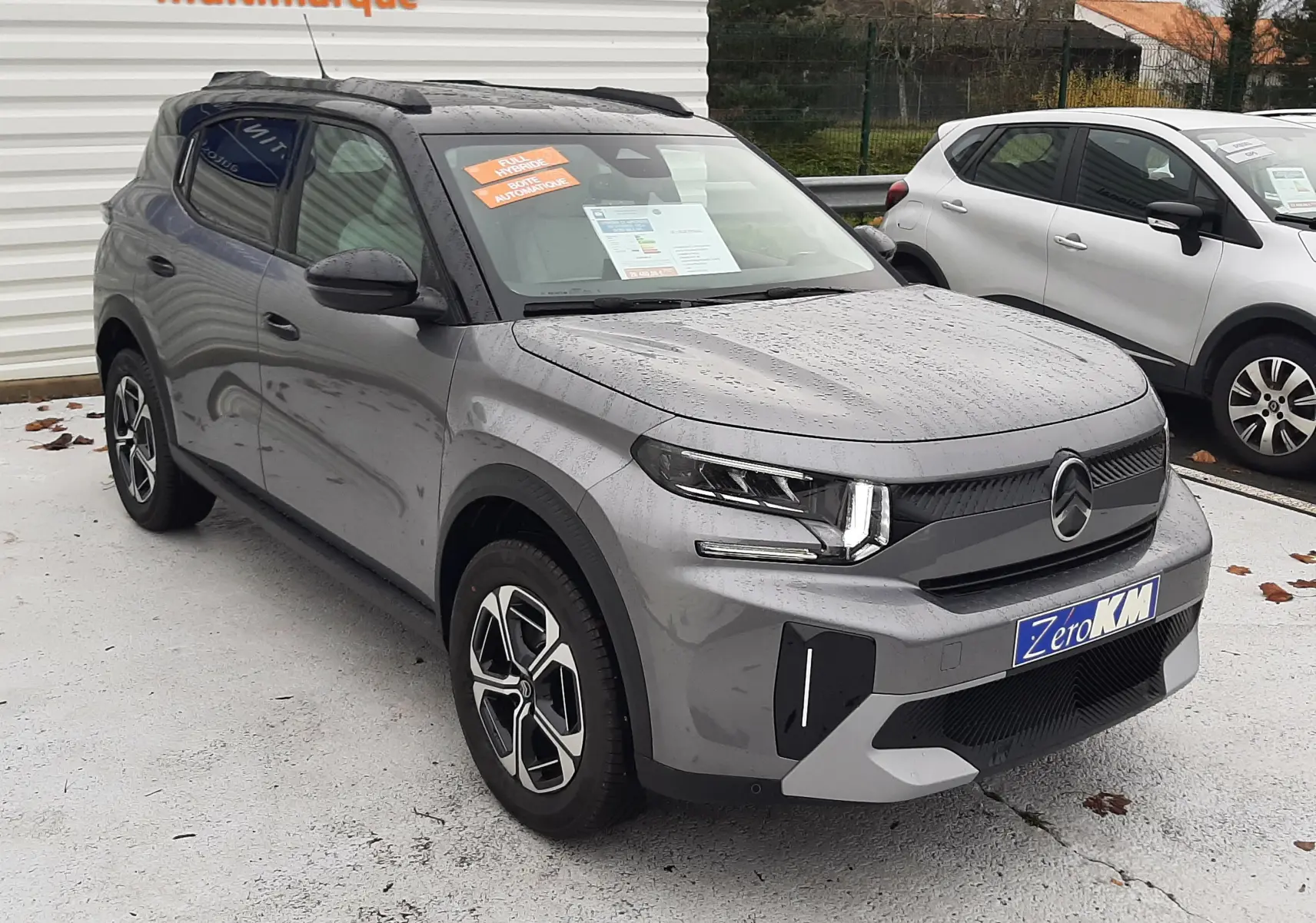 Citroën C3 Aircross hybride gris avec toit noir, vue 3/4 avant droit sous la pluie, jantes bi-ton distinctives.