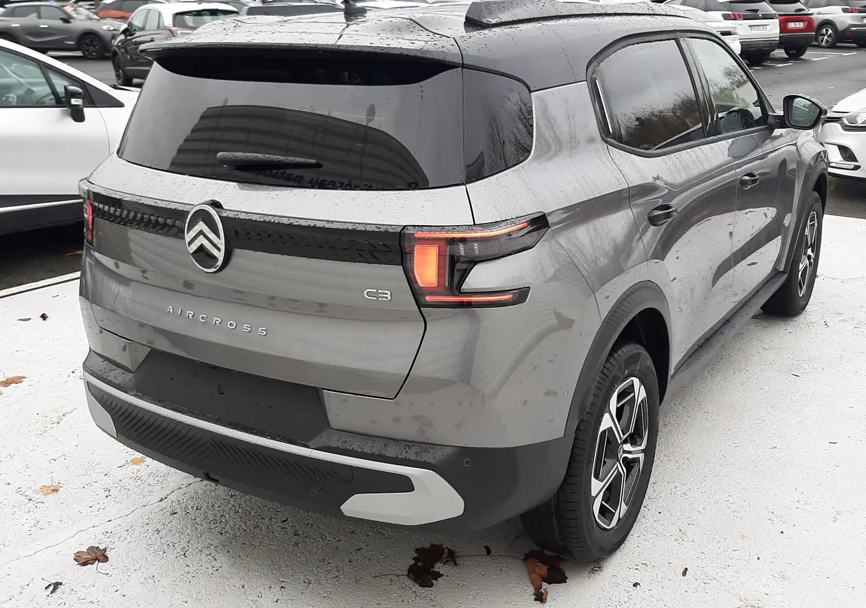 Vue 3/4 arrière droite d'un Citroën C3 Aircross 2025 gris avec toit noir, feux LED et jantes biton.