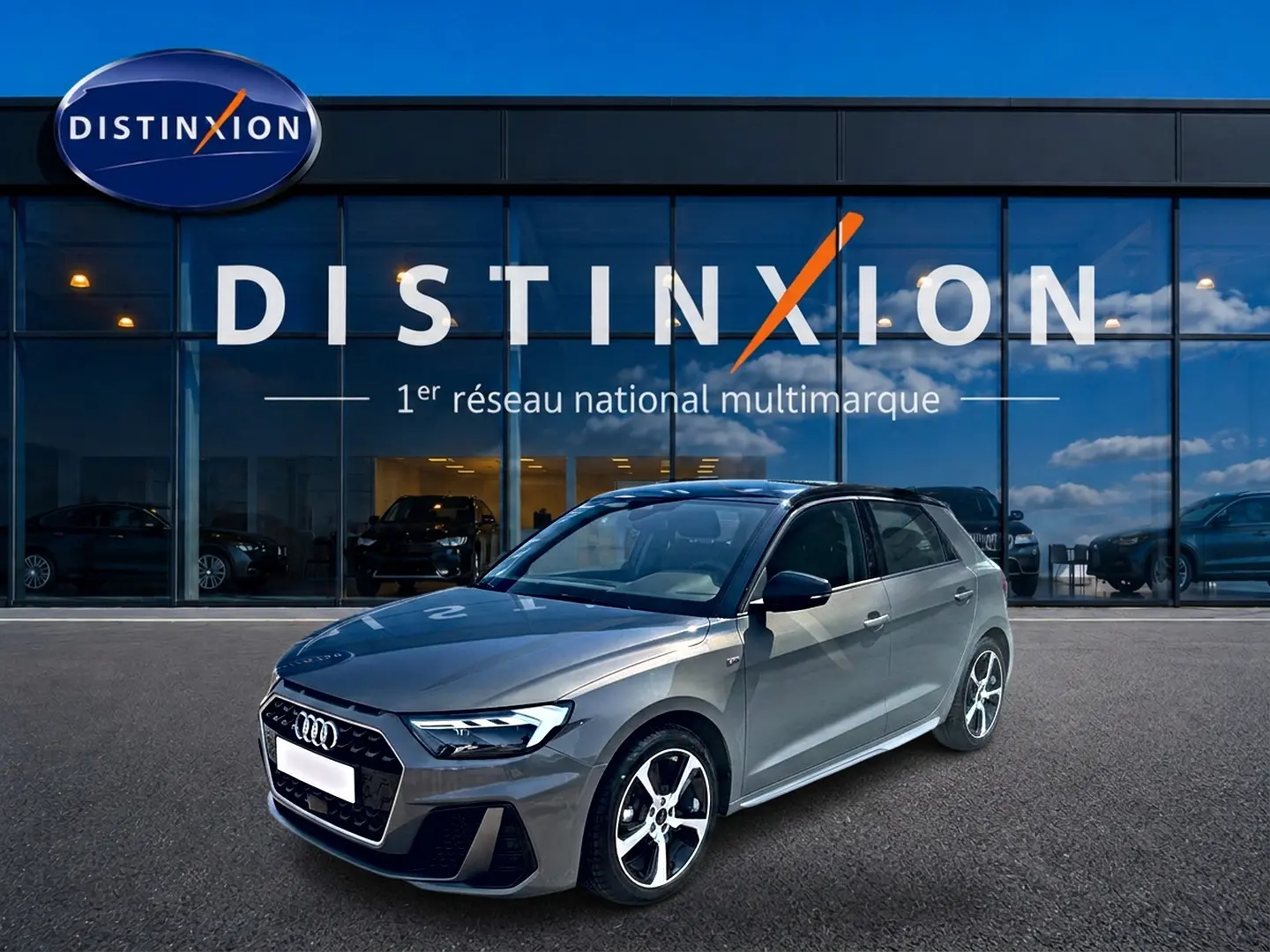 Audi A1 Sportback gris chronos vue 3/4 avant droit, avec jantes alu et toit noir devant vitrine Distinxion.