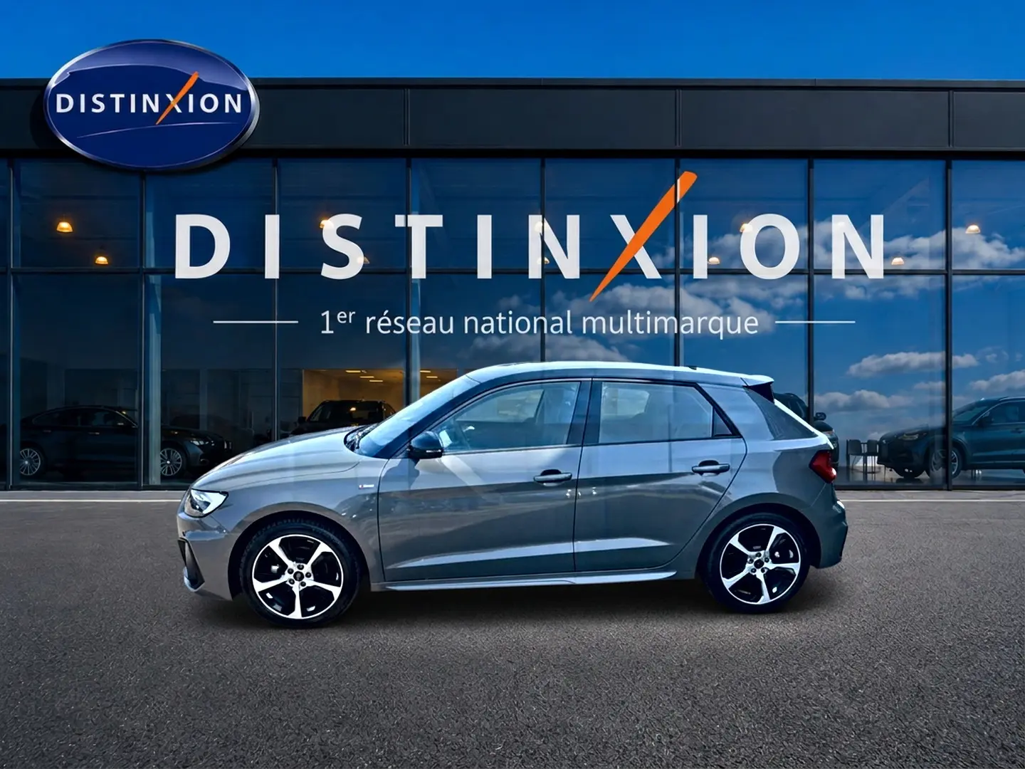 Audi A1 Sportback gris chronos vue de profil côté gauche, avec jantes alu et toit noir devant showroom Distinxion.