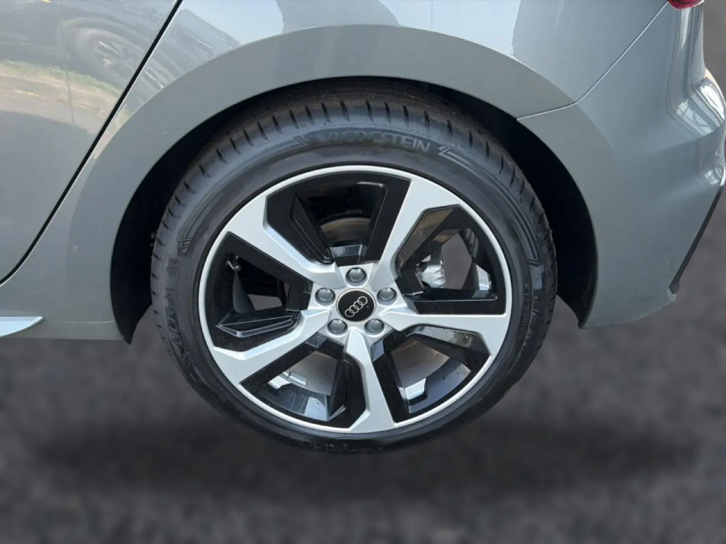 Gros plan sur la roue arrière droite d'une Audi A1 Sportback gris chronos avec jante alu bicolore.