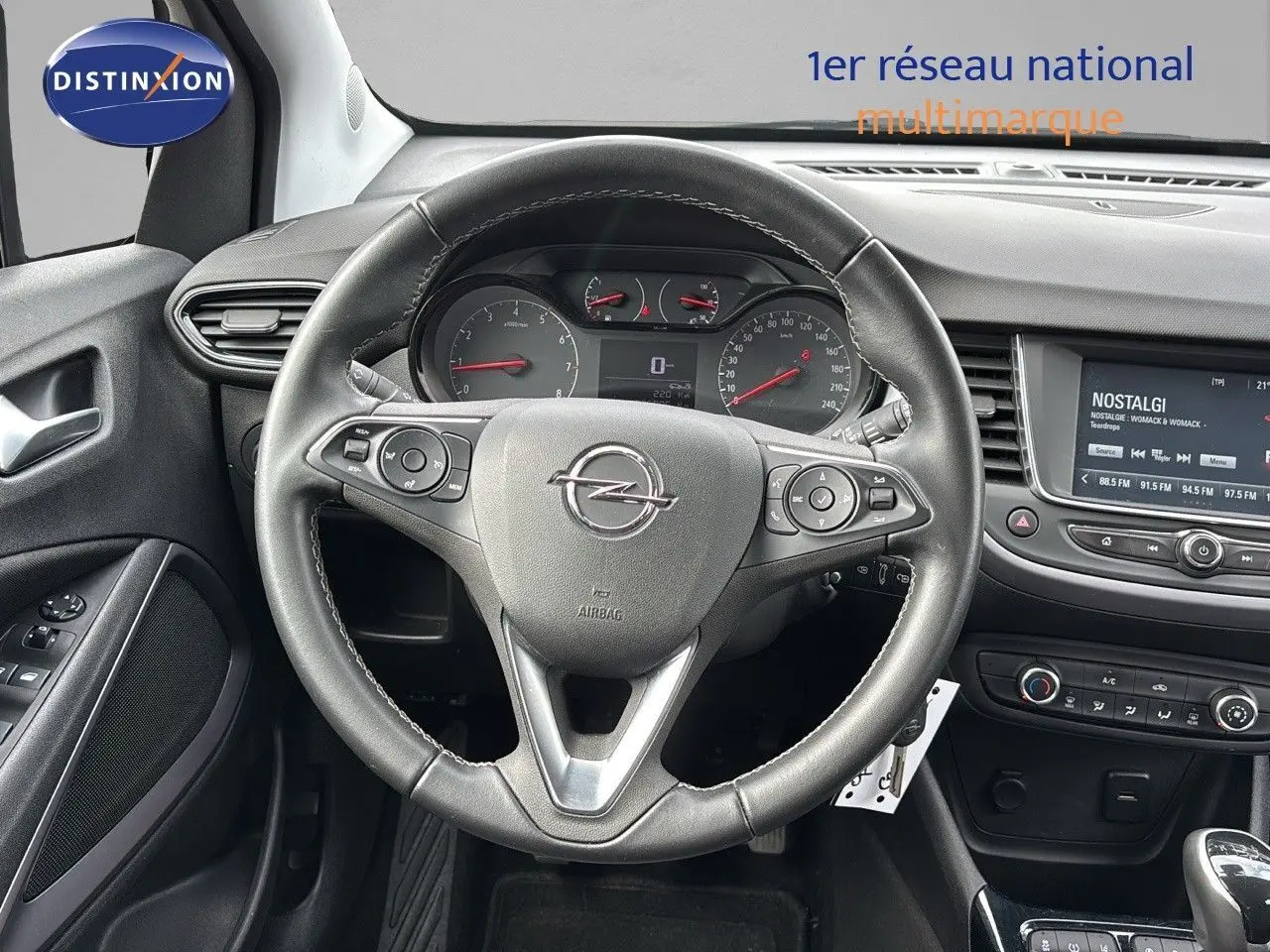 Vue centrée sur le volant cuir d'une Opel Crossland X gris pierre de lune, tableau de bord et écran multimédia visibles.